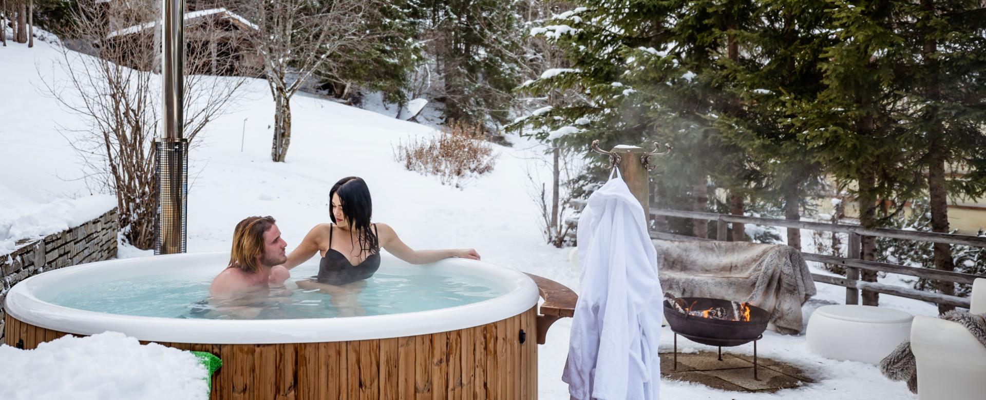 Couple relaxing in outdoor jacuzzi in the snow.