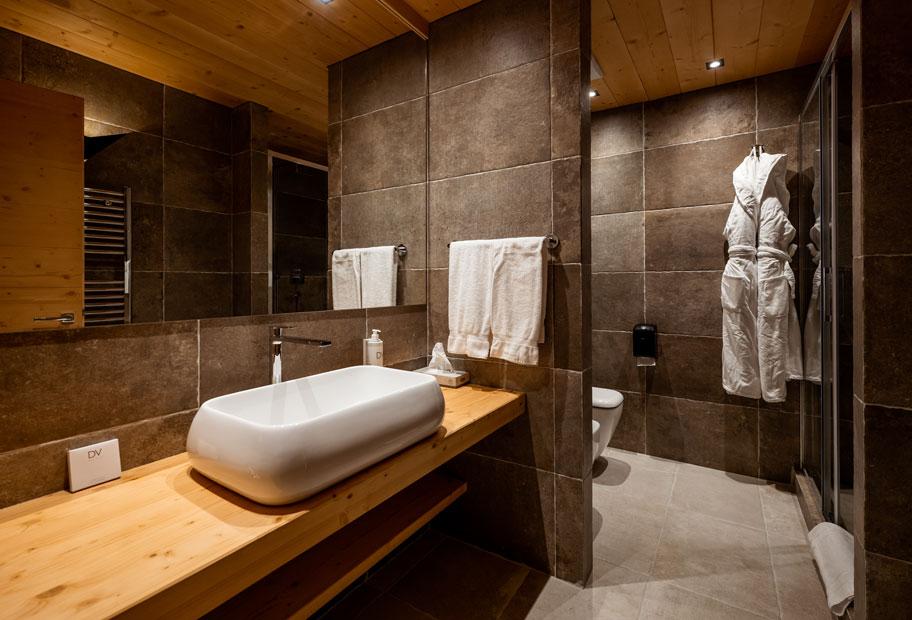 Bagno moderno con lavabo bianco e pareti in pietra.