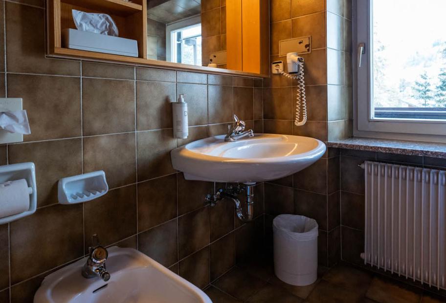 Bagno con bidet, lavabo, specchio e finestra.