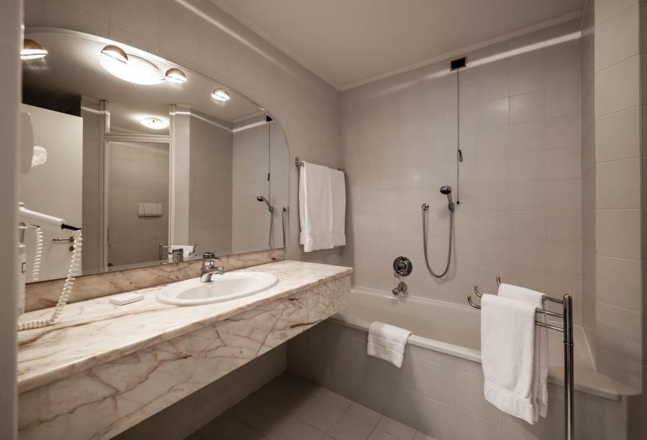 Bagno moderno con vasca, specchio grande e lavandino in marmo.