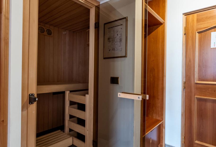 Sauna in legno con porta in vetro, all'interno di una casa.